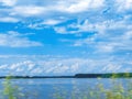 The summer scene in motion of the field grass in front of the lake and the sky. Royalty Free Stock Photo