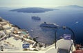 Summer scene with volcanic caldera of Santorini with white Greek houses and cruising tourist ships