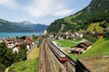 Summer scenery of beautiful Lake Lucerne on a sunny day, with a train traveling on the railway thru Sisikon Village Royalty Free Stock Photo