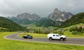 Summer scenery of Dolomiti with villages on the grassy hillside of rugged mountains & cars traveling on a highway Royalty Free Stock Photo