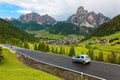 Summer scenery of Dolomiti with villages on the grassy hillside of rugged mountains & cars traveling on a highway Royalty Free Stock Photo