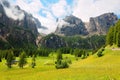 Summer scenery of majestic Sella mountains with waterfalls tumbling down rocky cliffs into a beautiful green grassy valley