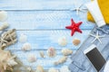 Summer sea beach concept. Top view blue wooden planks with seashells, rocks, sand and sunblock cream. White phone with Royalty Free Stock Photo