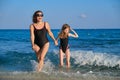 Mother and daughter child in swimsuits walking along seashore holding hands Royalty Free Stock Photo