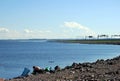 Along the Bank of the Neva Bay on the ring ROAD, a fisherman sits on the shore with a fishing rod.