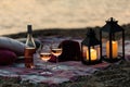 Summer sea sunset. Romantic picnic on the beach. Bottle of wine, glasses, candles, plaid and pillows. Royalty Free Stock Photo