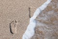 Summer sea wave with sea foam washes away footprints