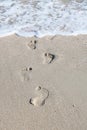 Summer sea wave with sea foam washes away footprints