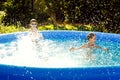 Summer season concept background. Happy friends are having fun splashing in an inflatable pool in the garden, refreshing Royalty Free Stock Photo