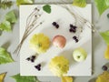 Summer seasonal composition of fruits, vegetables, flowers on a white plate and green tinted paper Royalty Free Stock Photo