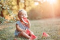 Summer seasonal picnic food. Cute Caucasian baby girl eating ripe red watermelon in park. Funny child kid sitting on ground with Royalty Free Stock Photo