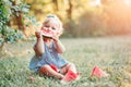 Summer seasonal picnic food. Cute Caucasian baby girl eating ripe red watermelon in park. Funny child kid sitting on ground with Royalty Free Stock Photo