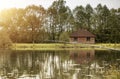 Summer serene landscape with lake, fishing rod and wooden house