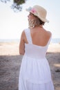 Summer Serenity: Girl in White Dress with Straw Hat and Flowers by the Sea