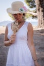 Summer Serenity: Barefoot Girl in White Dress with Straw Hat and Flowers by the Sea