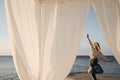 Summer shot, through white canopy on seashore of caucasian young pretty girl standing on pier. Royalty Free Stock Photo