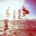 Summer silhouettes of happy young people jumping in sea on the b Royalty Free Stock Photo