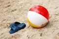 Summer slippers and Beach ball in sand