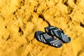 Summer slippers. Navy blue flip flop on yellow sand beach background. Copy space, top view. Holiday and travel concept Royalty Free Stock Photo