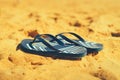 Summer slippers. Navy blue flip flop on yellow sand beach background. Copy space, top view. Holiday and travel concept Royalty Free Stock Photo