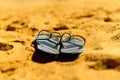 Summer slippers. Navy blue flip flop on yellow sand beach background. Copy space, top view. Holiday and travel concept Royalty Free Stock Photo