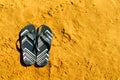 Summer slippers. Navy blue flip flop on yellow sand beach background. Copy space, top view. Holiday and travel concept Royalty Free Stock Photo