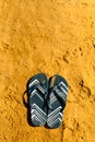 Summer slippers. Navy blue flip flop on yellow sand beach background. Copy space, top view. Holiday and travel concept Royalty Free Stock Photo