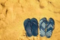 Summer slippers. Navy blue flip flop on yellow sand beach background. Copy space, top view. Holiday, vacation and travel Royalty Free Stock Photo