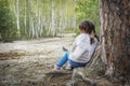 In summer, a small angel is leaning against a tree in the forest Royalty Free Stock Photo