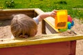 Heat. A little blond boy of three years old tiredly lay down on a sandbox board, playing with his machine in the sand Royalty Free Stock Photo