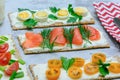 Summer snacks closeup. Light sandwiches from crispy bread. Various fillings, tomatoes, herbs, curd cheese and trout. Royalty Free Stock Photo