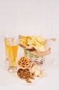 Summer snacks and lager beer in glass - nachos, croutons, chips, tortilla in rustic basket and paper corners on white wood backgr Royalty Free Stock Photo