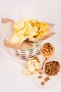 Summer snacks - nachos, croutons, chips, tortilla in rustic basket and paper corners on white wood background.