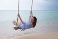 Summer solar portrait of fashion of a way of life of the young stylish woman,sitting on a swing on the beach,carrying lovely fashi Royalty Free Stock Photo