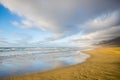 Summer solitary beach with water reflections concept - beautiful landscape with ocean and waves - blue sky and mountains in