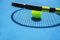 Summer sport concept with tennis ball and racket on blue hard tennis court. Royalty Free Stock Photo