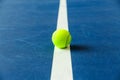 Summer sport concept with tennis ball on white line on hard tennis court blue color. Flat lay, top view, copy space Royalty Free Stock Photo