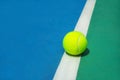 Summer sport concept with tennis ball on white line on hard tennis court. Royalty Free Stock Photo