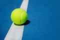 Summer sport concept with tennis ball on white line on hard tennis court.