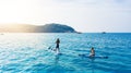 Summer is for stand up paddle boarding. a man and woman paddle boarding across the sea.