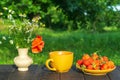 Summer still life of a plate with strawberries and coffee on a table with flowers. Summer morning or evening background Royalty Free Stock Photo