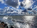 Summer storm at sea dramatic fluffy clouds on blue dark sky birds fly water wave splash on pier at Baltic sea on horizon Tallinn