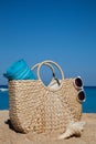 Summer straw bag with blue towel and sunglasses on a tropical sa Royalty Free Stock Photo