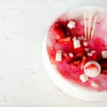 Summer strawberry mousse cake, fresh berries, coconut, and sweet decor element on top, white concrete background Royalty Free Stock Photo