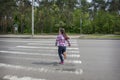 In the summer, on the street, a little girl crosses the road on a pedestrian crossing Royalty Free Stock Photo