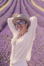 Summer style portrait of cute middle age woman smiling and having fun with violet flowers of lavender fields in background - Royalty Free Stock Photo