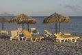 Summer sun beds and umbrellas on sandy Greece beach at evening. Seaside with parasols.