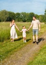 Summer sunny day for a young family, dad, mom and little girl became joyful and happy. Beautiful flower meadow, happy Royalty Free Stock Photo
