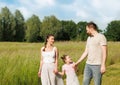 Summer sunny day for a young family, dad, mom and little girl became joyful and happy. Beautiful flower meadow, happy Royalty Free Stock Photo