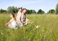 Summer sunny day for a young family, dad, mom and little girl became joyful and happy. Beautiful flower meadow, happy Royalty Free Stock Photo